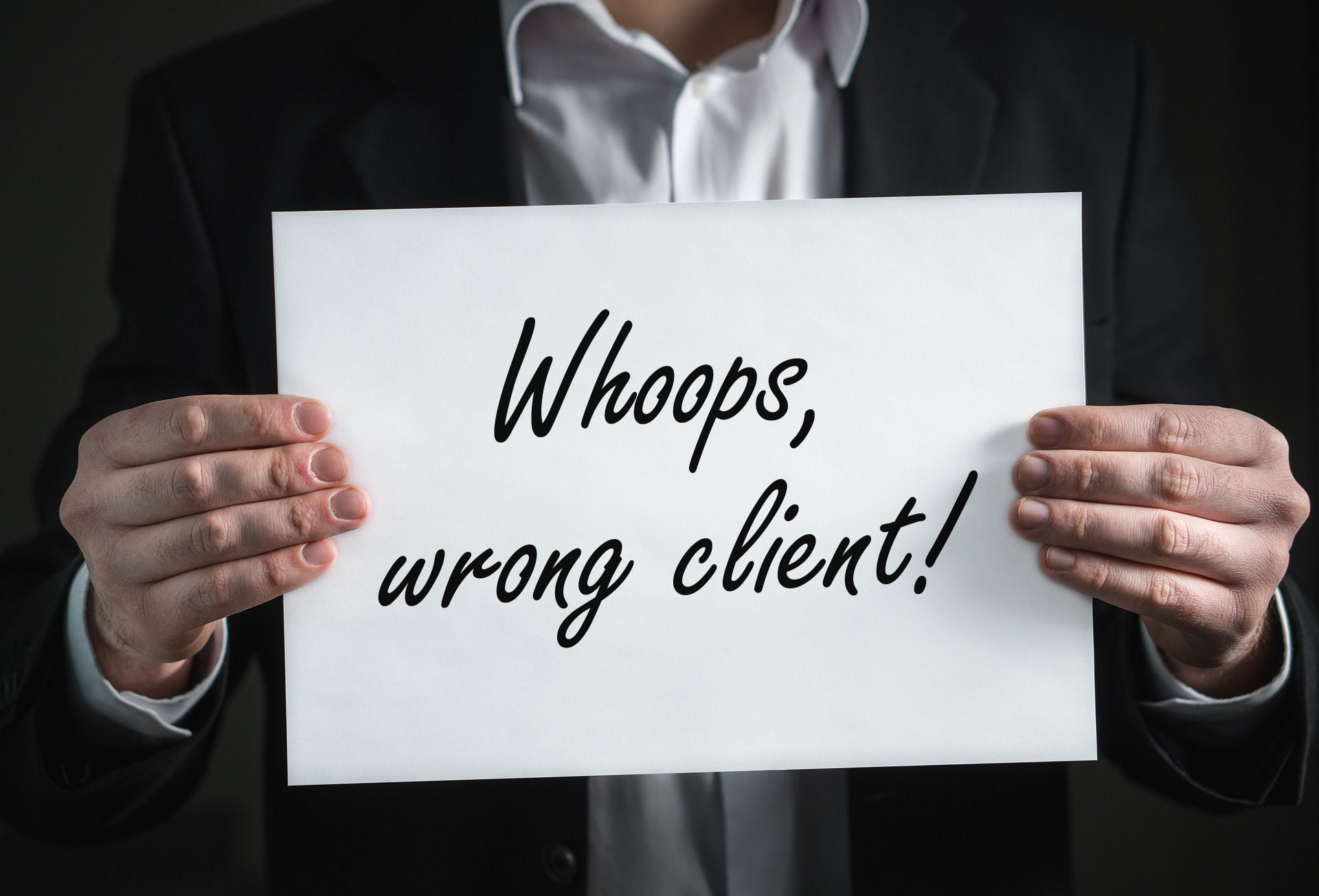 A person holding a sign that says "Whoops, wrong client!"